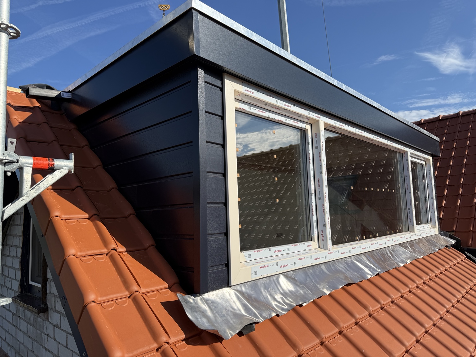 Geplaatste prefab dakkapel met donkere gevelbekleding en lichte kunststof kozijnen