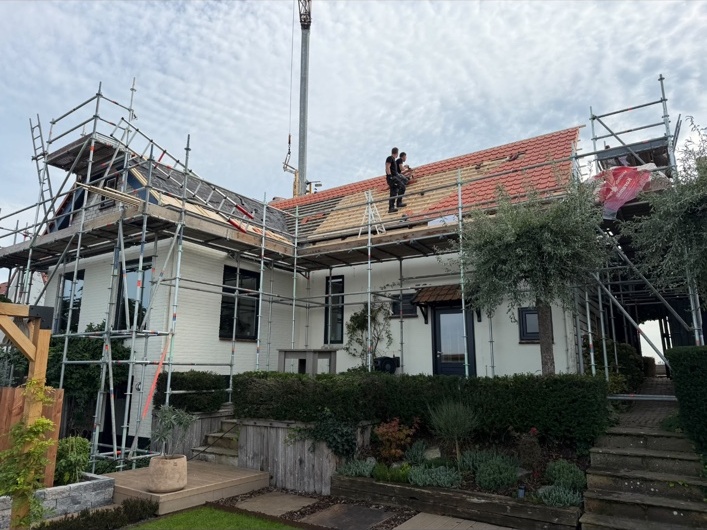 Dakrenovatie in uitvoering, met steigers rondom de woning en werkzaamheden aan het pannendak
