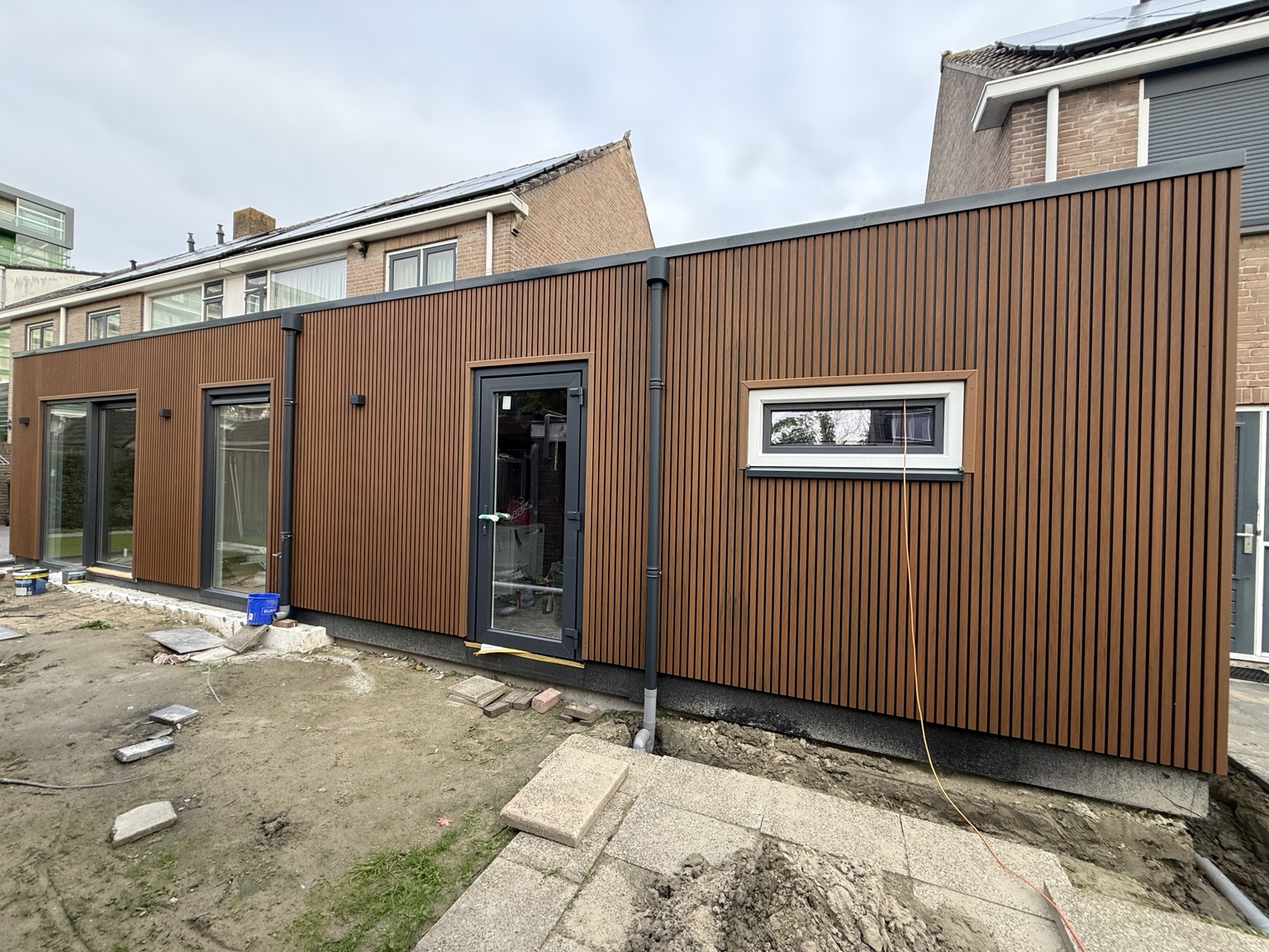 Eigen project van VZ bouwpartners: aanbouw met verticale bruine gevelbekleding en donkere kozijnen